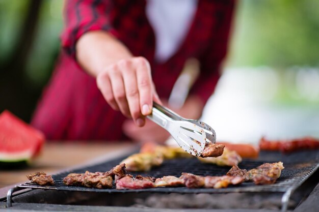 Uomo che cucina cibo gustoso sulla griglia del barbecue per una cena francese all'aperto vicino al fiume in una bella serata estiva nella natura