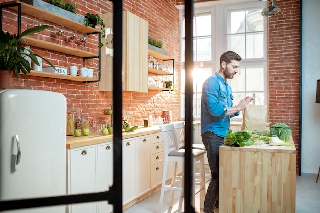 Uomo che cucina cibo sano in piedi sulla cucina del bellissimo appartamento loft