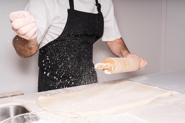 Uomo che cucina croissant fatti in casa preparando la pasta sfoglia e aggiungendo la farina