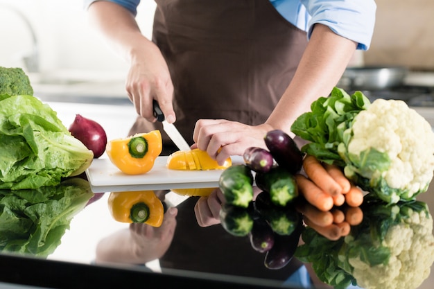 Uomo che cucina e prepara insalata in cucina