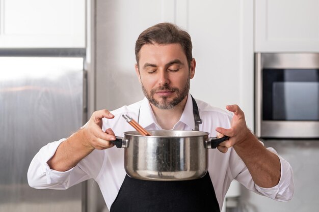 Uomo che cucina in cucina uomo bello che prepara un delizioso pasto in cucina moderna cuoco maschio che cucina in