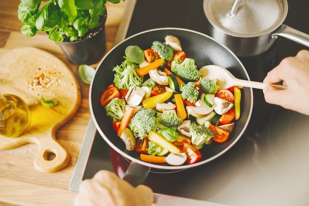 Uomo che cucina verdure fresche sulla padella