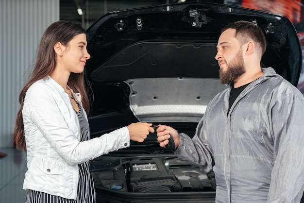 Uomo che dà le chiavi del cliente alla sua auto riparata nel servizio di riparazione auto