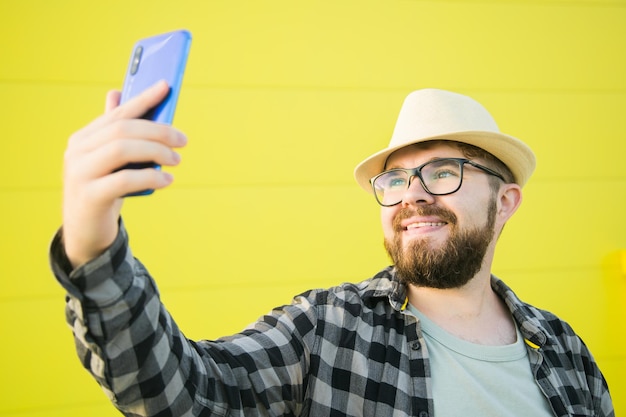 Uomo che dice qualcosa alla telecamera mentre viaggia in una nuova città gialla sullo sfondo del muro di strada Concetto di blogger e vlog