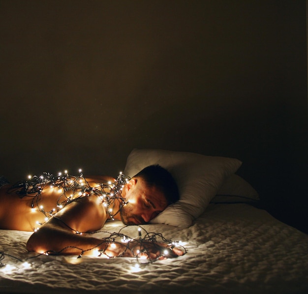 Uomo che dorme con le luci accese sul letto a casa