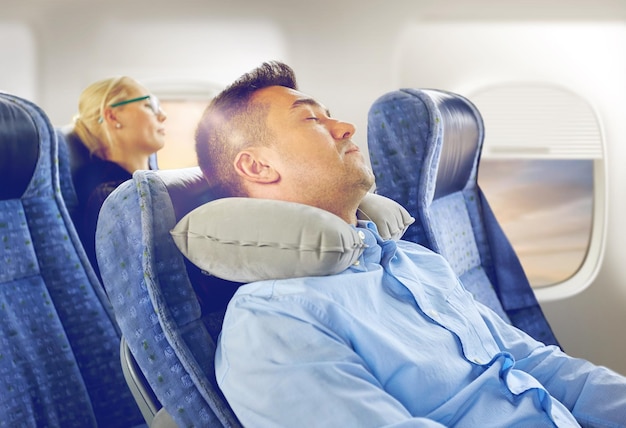 uomo che dorme in aereo con un cuscino per il collo cervicale