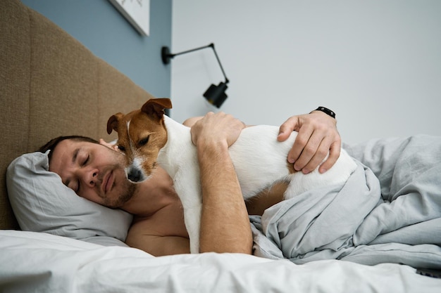 Uomo che dorme sul letto con il cane Pet affetto