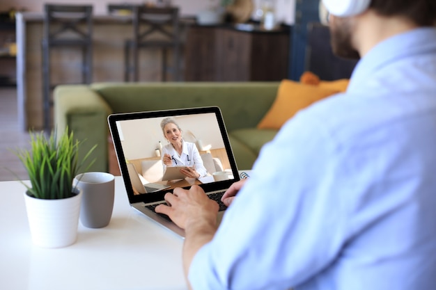 Uomo che effettua una videochiamata con il suo medico durante l'autoisolamento e la quarantena Consultazione online