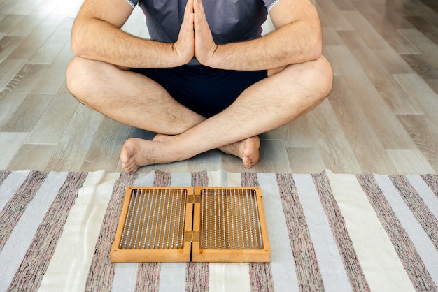 Uomo che esercita yoga meditazione seduta mani unite sul pavimento vicino a una tavola di sadhu