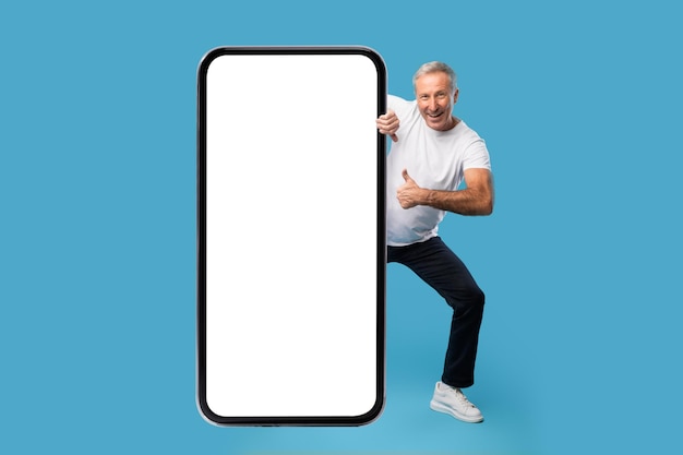 Uomo che fa capolino dal grande mockup bianco dello schermo dello smartphone vuoto