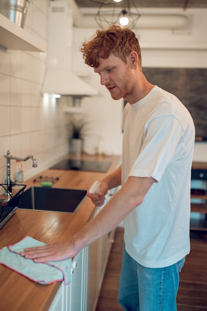 Uomo che fa dei lavori domestici e pulisce alcune superfici