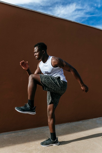 Uomo che fa esercizi di stretching contro il muro marrone