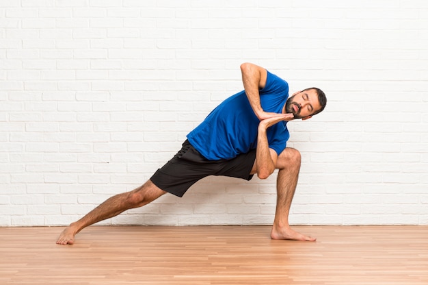 Uomo che fa esercizi di yoga al chiuso