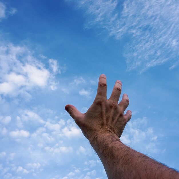 uomo che fa gesti e raggiunge il cielo blu