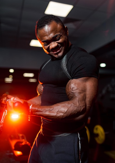 Uomo che fa gli esercizi in palestra Foto di giovane uomo in camicia nera su sfondo palestra moderna Forza e motivazione