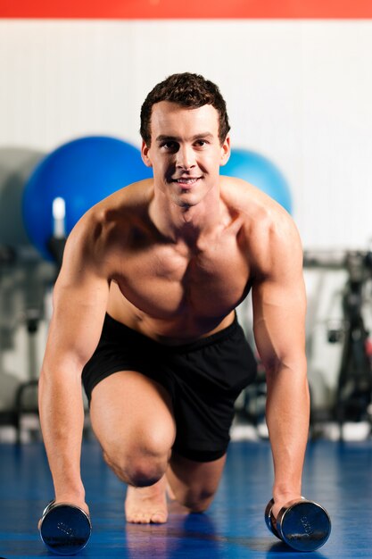 Uomo che fa i piegamenti sulle braccia in palestra