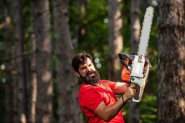 Uomo che fa il lavoro dell'uomo tema dell'agricoltura e della silvicoltura bel giovane con ascia vicino alla foresta il legname