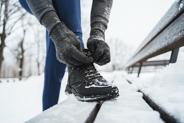 Uomo che fa jogging allaccia le scarpe durante il suo allenamento invernale in un parco cittadino
