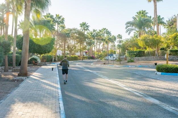 Uomo che fa jogging sulla strada con palme vicino al mare