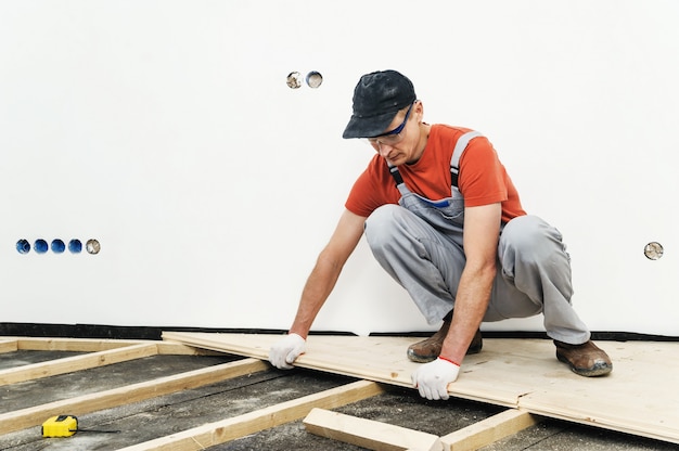 uomo che fa l'installazione del pavimento in legno.