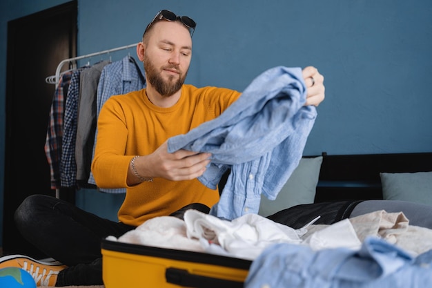 Uomo che fa le valigie per il viaggio nella camera da letto Concetto di viaggio