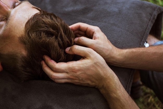 Uomo che fa massaggio osteopatico alla testa e al collo in natura 5