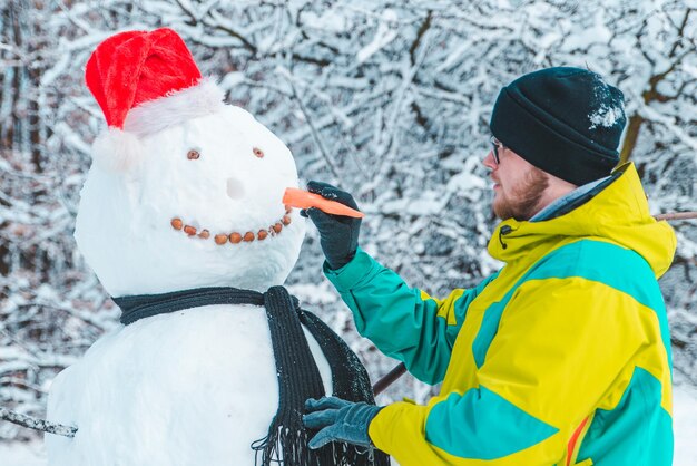 Uomo che fa pupazzo di neve all'aperto al concetto di parco invernale gelido