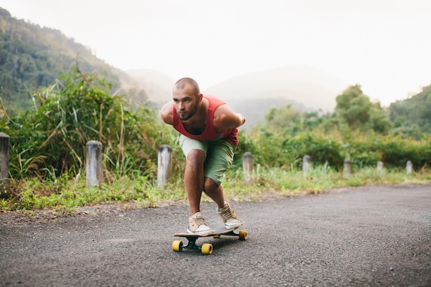 Uomo che fa skateboard sulla strada contro la montagna