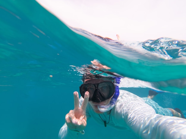 Uomo che fa snorkeling sott'acqua blu chiaro copia spazio concetto di viaggio e vacanza