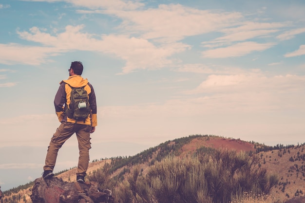 Uomo che fa un'escursione alle montagne del tramonto con uno zaino leggero