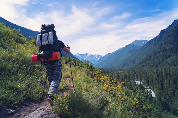 Foto uomo che fa un'escursione alle montagne del tramonto con uno zaino pesante travel lifestyle wanderlust avventura concetto vacanze estive all'aperto da solo in natura. bastoncini da nordic walking.
