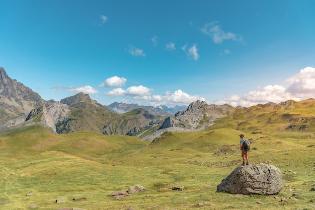 Uomo che fa un'escursione in cima a una roccia in una bellissima valle tra le montagne durante la scoperta del tramonto