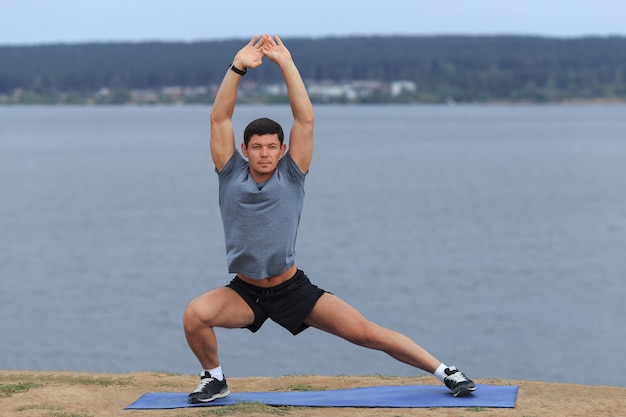 Uomo che fa yoga all'aperto. Giovane che pratica esercizio di fitness yoga all'aperto nel bellissimo mare. Meditazione e relax
