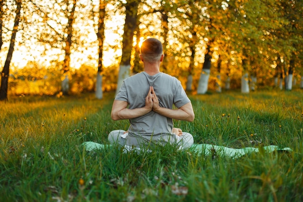 Uomo che fa yoga nel parco su un bel tramonto. Uno stile di vita sano