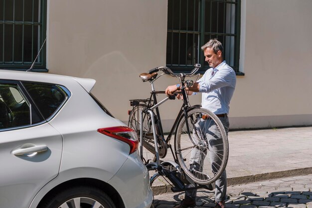 Uomo che fissa la bicicletta sul rimorchio all'auto