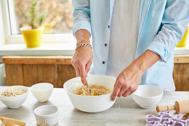 Uomo che forma la pasta nella ciotola e impasta a casa