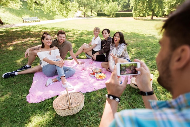 uomo che fotografa gli amici tramite smartphone al picnic