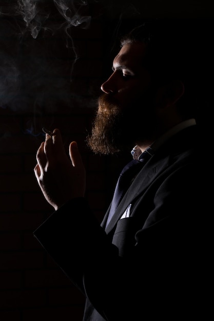 Uomo che fuma sigaretta isolato su nero un uomo fuma erba di cannabis una canna e un accendino in mano