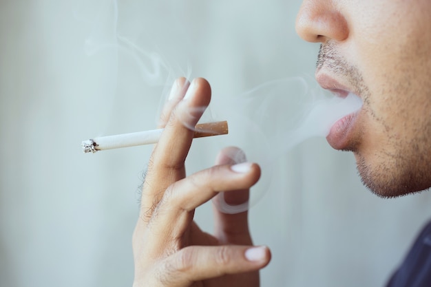 Uomo che fuma una sigaretta. Diffusione del fumo di sigaretta.