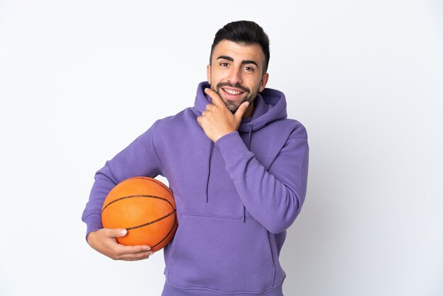 Uomo che gioca a basket sul muro bianco felice e sorridente