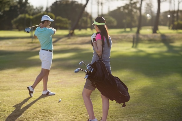 Uomo che gioca a golf con la borsa di trasporto della donna