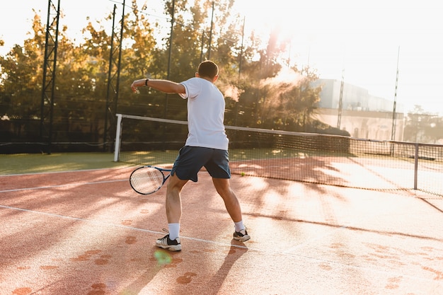 Uomo che gioca a tennis al mattino al sole