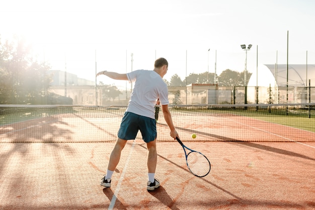 Uomo che gioca a tennis al mattino al sole