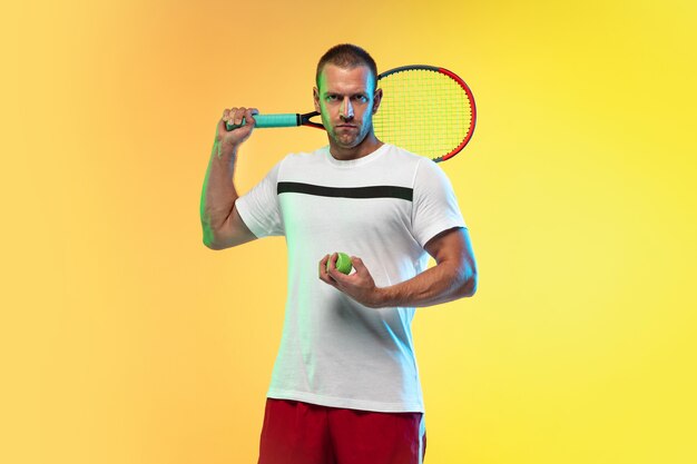 Uomo che gioca a tennis isolato su studio in luce al neon