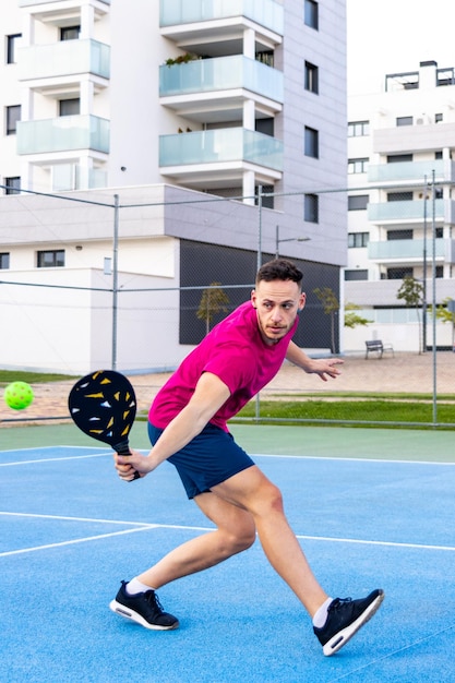 uomo che gioca al gioco del pickleball colpendo la palla del pickleball con l'attività sportiva all'aria aperta della pagaia