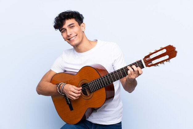 Uomo che gioca chitarra sopra la parete isolata