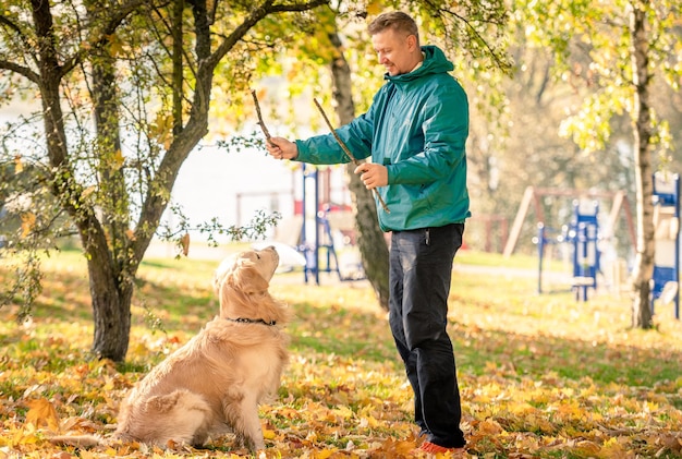 Uomo che gioca con il suo cane golden retriever nel parco