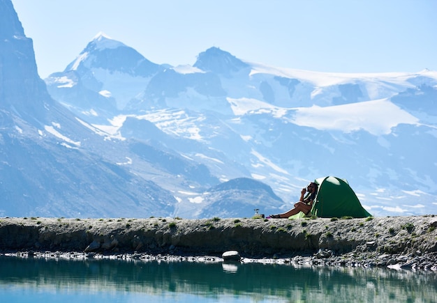 Uomo che gode del paesaggio delle montagne vicino alla tenda