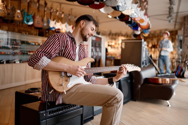 Uomo che gode del suono mentre suona la chitarra collegata all'amplificatore