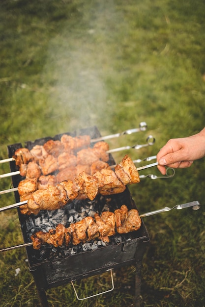 Uomo che griglia a mano barbecue con maiale affumicato nel cortile sul giorno cena in famiglia in stile barbecue all'aperto attività